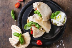 Pity pszenne z kurczakiem i warzywami wyłożona na czarnym talerzu