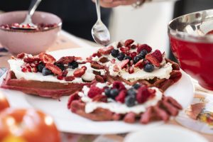 Gofry różowe z burakiem, na wierzchu jogurt i maliny, borówki.