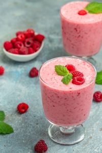 smoothie malinowe w pucharku z listkami mięty i świeżymi malinami