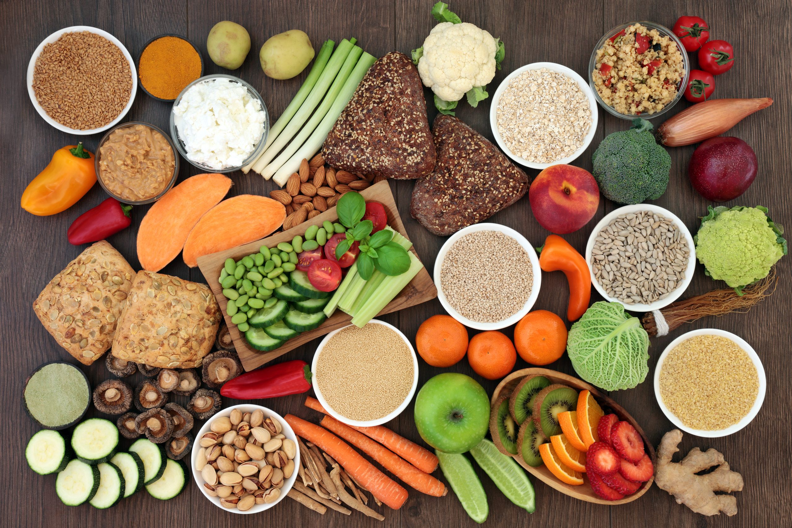 Health food for vegans with grains, seeds, nuts, peanut butter, almond yoghurt, herbs, spice, vegetables, fruit, cereals, wholegrain bread rolls. High in antioxidants, protein, dietary fibre & omega 3 Zdjęcie z góry produktów zawierających błonnik